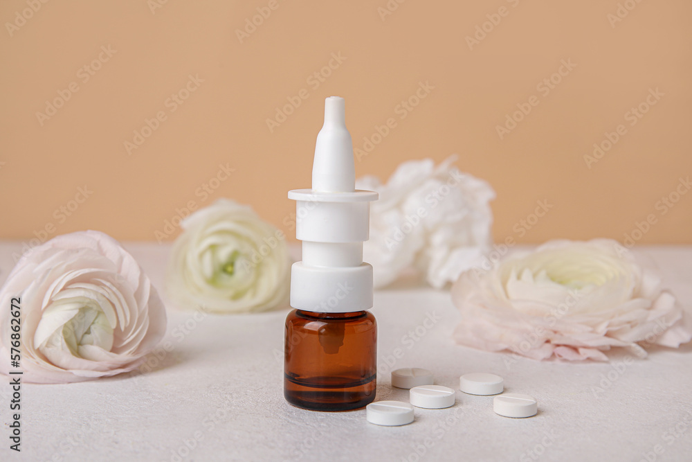 Nasal drops with pills and flowers on table near beige wall, closeup. Seasonal allergy concept Nasal drops with pills and flowers on table near beige wall, closeup. Seasonal allergy concept