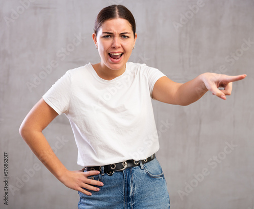 Принти на полотні Photo of aggressive young woman banishing crossly standing against light unicolo