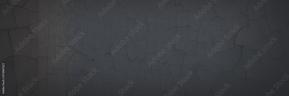 Dark wide panoramic background. Peeling paint on a concrete wall. Faded dark texture of old cracked flaking paint. Weathered rough painted surface with patterns of cracks. Shaded background for design