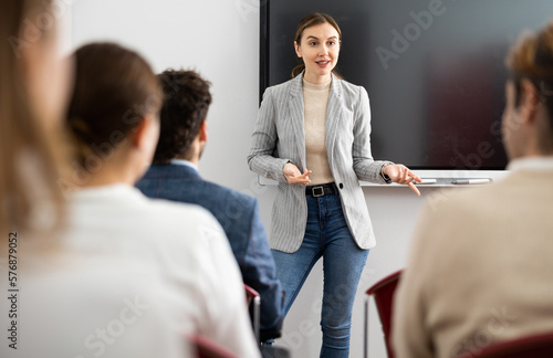 Quadro su tela Young female professor explaining subject to classroom full of students