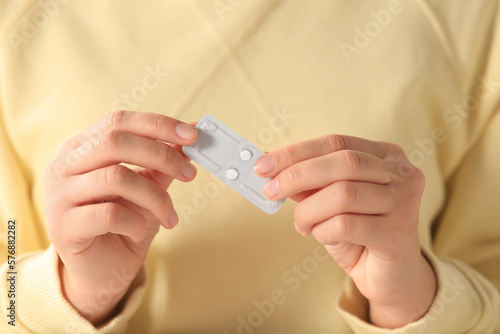 Woman holding blister of emergency contraception pills on white background  closeup