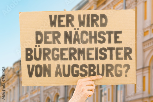 Wallpaper Mural The phrase " Who's the next mayor of Augsburg? " on a banner in men's hands blurred the background. Election. City management. Politics. Urban. Voter. Candidate Torontodigital.ca