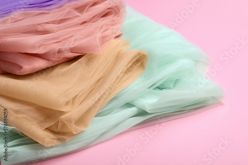 Beautiful colorful tulle fabrics on pink background, closeup