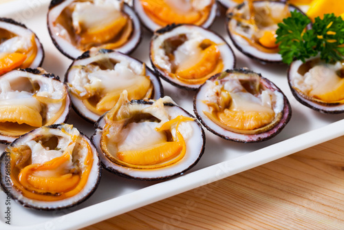 Raw bivalve mollusks (European bittersweet) served with lemon on plate
