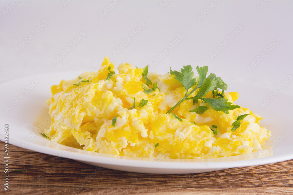 Scrambled eggs on plate, wooden table, front view Scrambled eggs on plate, wooden table, front view
