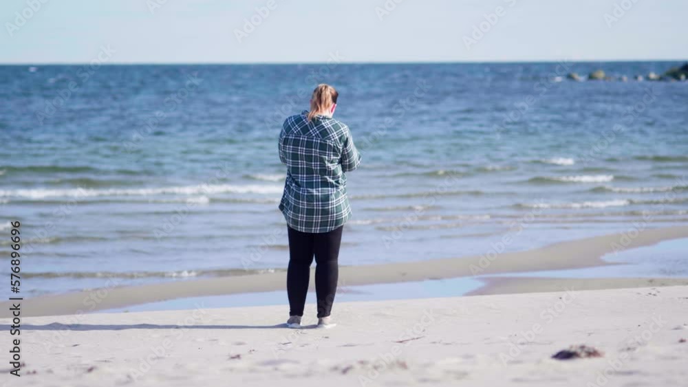 Women standing on the beach taking photos of the ocean Women standing on the beach taking photos of the ocean