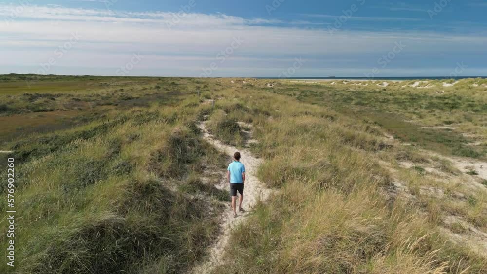 Aerial Follow of Male walking on sand path amongs sand dunes Aerial Follow of Male walking on sand path amongs sand dunes