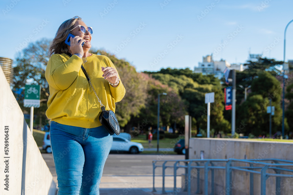 Fototapeta premium Talking in Style: Beautiful Curvy Latina Walking and Chatting outdoor in the park. Copy space. Real Woman Empowerment- Body Positive concept. 