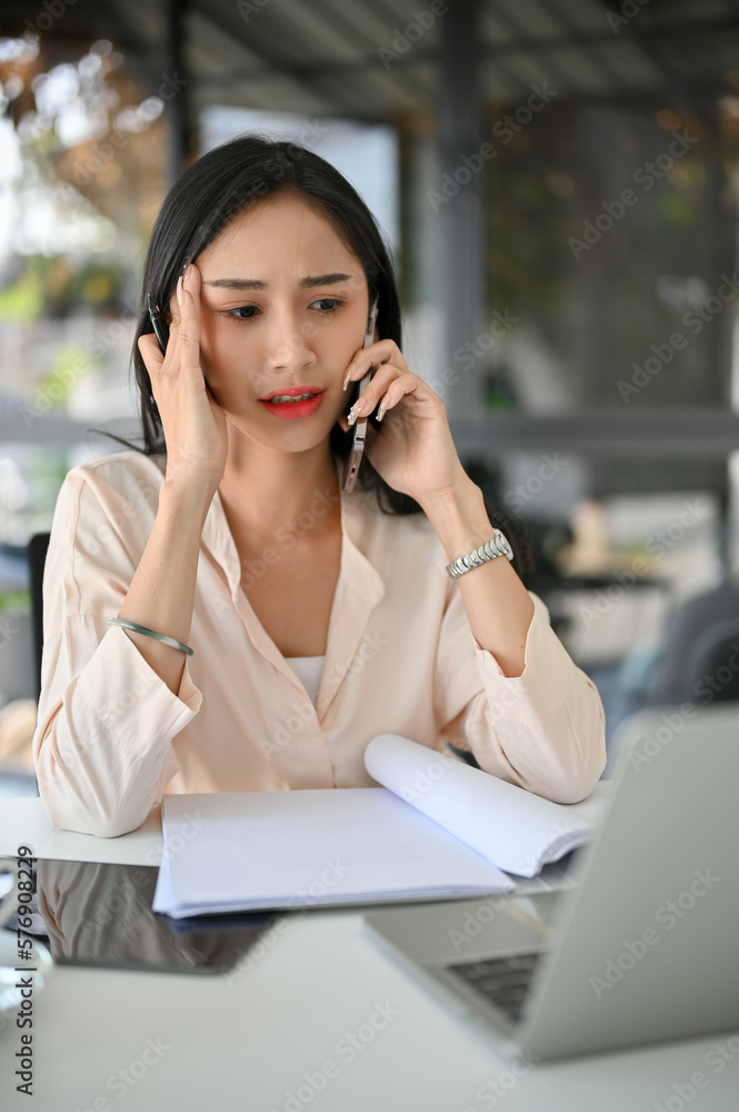Serious and stressed millennial Asian businesswoman is on the phone with someone Serious and stressed millennial Asian businesswoman is on the phone with someone