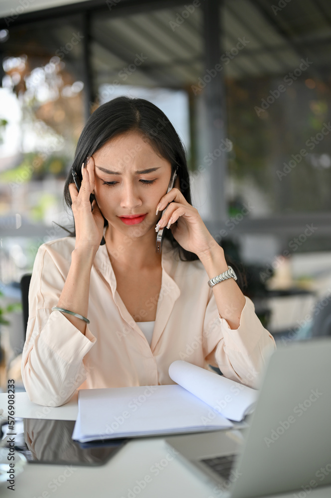 Serious and stressed millennial Asian businesswoman is on the phone, having a serious phone call Serious and stressed millennial Asian businesswoman is on the phone, having a serious phone call