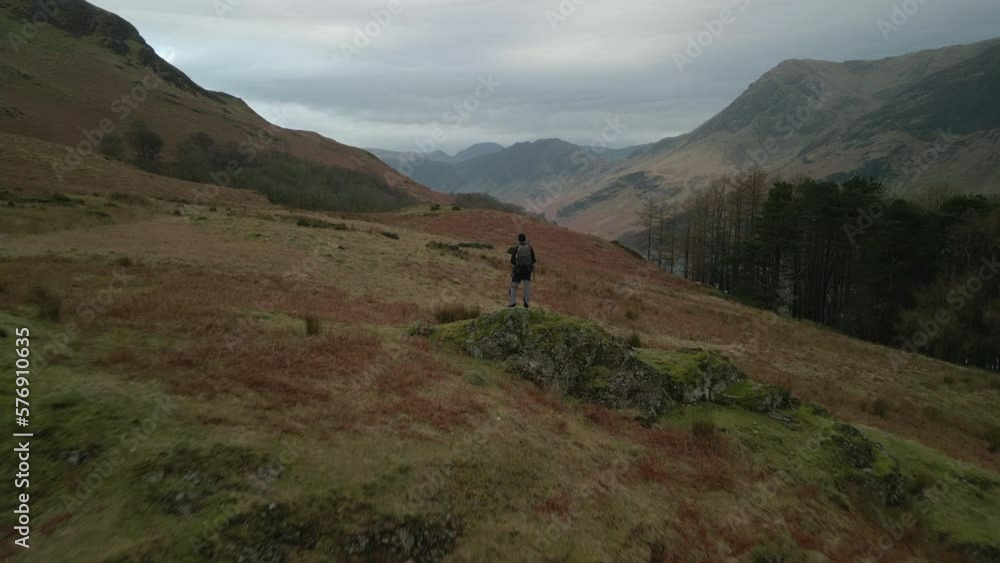 Flying past hiker on rocky outcrop towards distant misty mountains at Buttermere English Lake District UK Flying past hiker on rocky outcrop towards distant misty mountains at Buttermere English Lake District UK