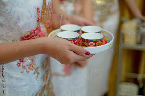 Canvas Print Chinese woman hand holding serving ceremonial tea set for a Chinese wedding ceremony cups, text calligraphy lllustration Ten thousand on the tea set a plate with traditionally porselain cups