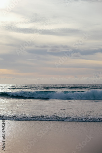 Ocean waves with cloudy sky over horizon.