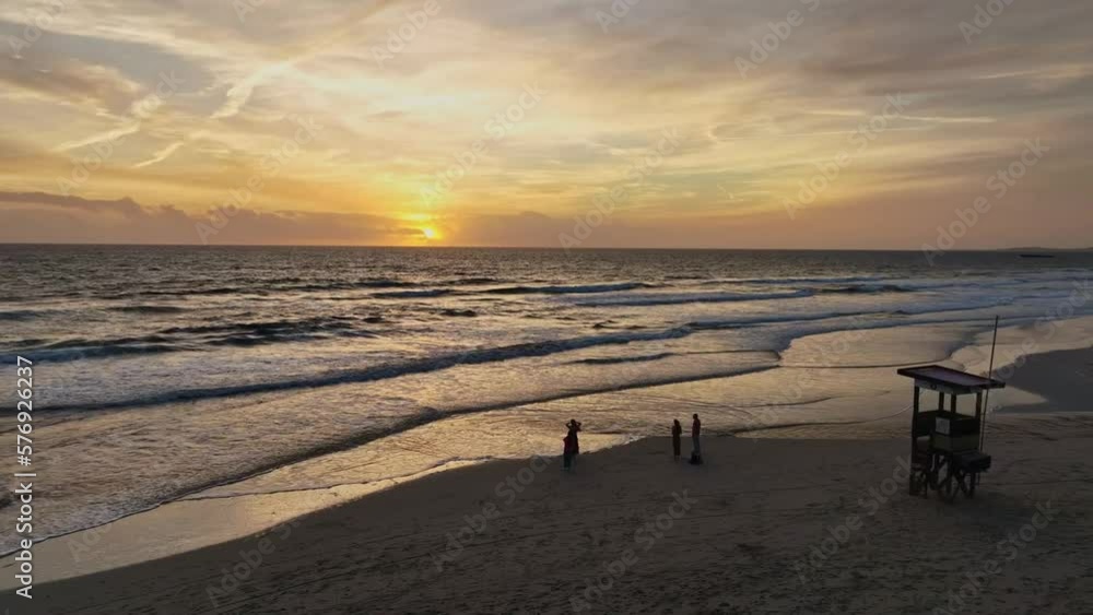 People watching sun set below the horizon in front of life guard tower on beach. People watching sun set below the horizon in front of life guard tower on beach.