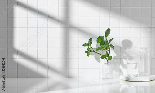 Various objects on a white tile background with warm sunlight shining through
