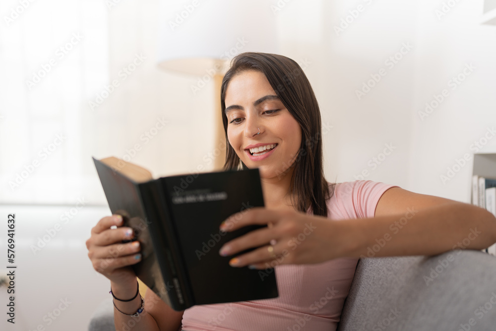 Young woman, laughing while reading her favorite book Young woman, laughing while reading her favorite book