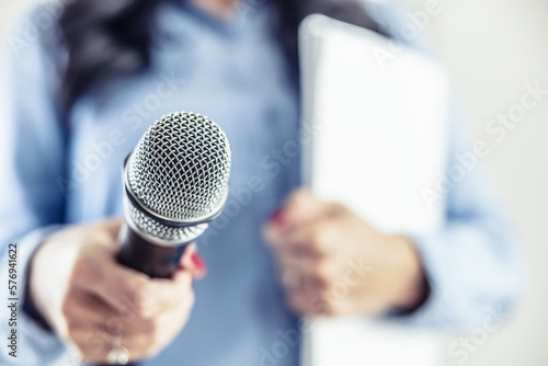 Investigative journalist with microphone in other hand notebook - Close up