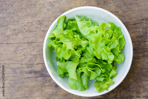 Vegetables or lettuce or green oak in a white bowl on a wooden background. Healthy food concept.