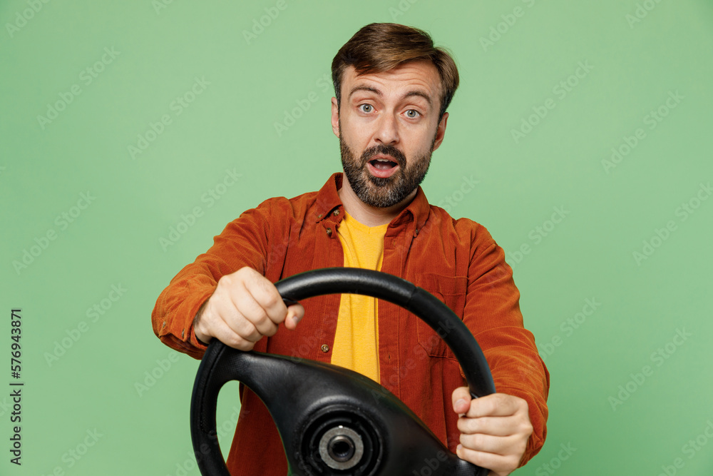 Elderly confused shocked sad man 40s years old he wearing casual clothes red shirt t-shirt hold steering wheel driving car look camera isolated on plain pastel light green background studio portrait. Elderly confused shocked sad man 40s years old he wearing casual clothes red shirt t-shirt hold steering wheel driving car look camera isolated on plain pastel light green background studio portrait.