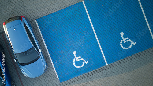 Outdoor car parking with handicapped symbol icon. Parking places reserved for disabled person. Aerial drone view