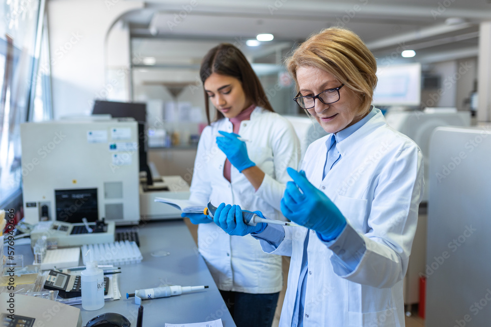 Modern Medical Research Laboratory: Female Scientist Working with Micro Pipette, Using Digital Tablet for Test Sample Analysis. Advanced Scientific Lab for Medicine, Biotechnology Development. Modern Medical Research Laboratory: Female Scientist Working with Micro Pipette, Using Digital Tablet for Test Sample Analysis. Advanced Scientific Lab for Medicine, Biotechnology Development.