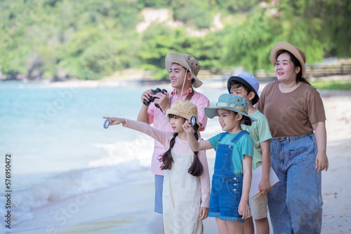 Group of teacher and school children on ecotourist trip and used binoculars learning show beach take care of environment is summer holiday camp save earth save world day concept. 