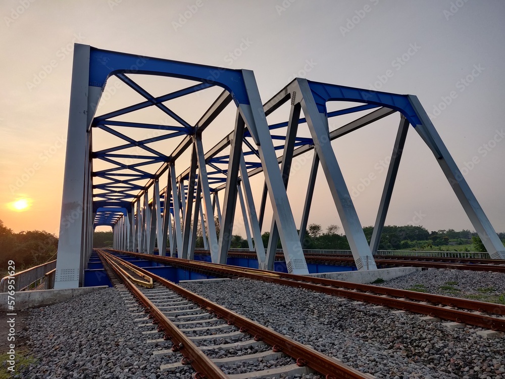 Twin Railway bridges over the river with the sunrise in the background Twin Railway bridges over the river with the sunrise in the background