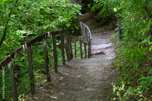 Long trail equipped with gravel steps and wooden handrail for tourists in sunny summer forest. Empty hiking path in Nature park reserve. photo