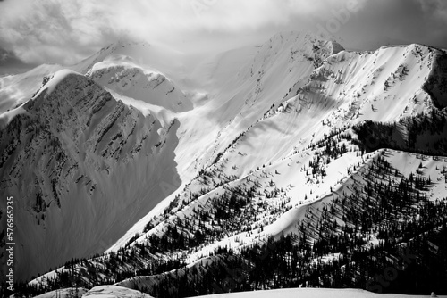 The sun peaks through the clouds illuminating a beautiful and rugged winty mountain landscape. photo