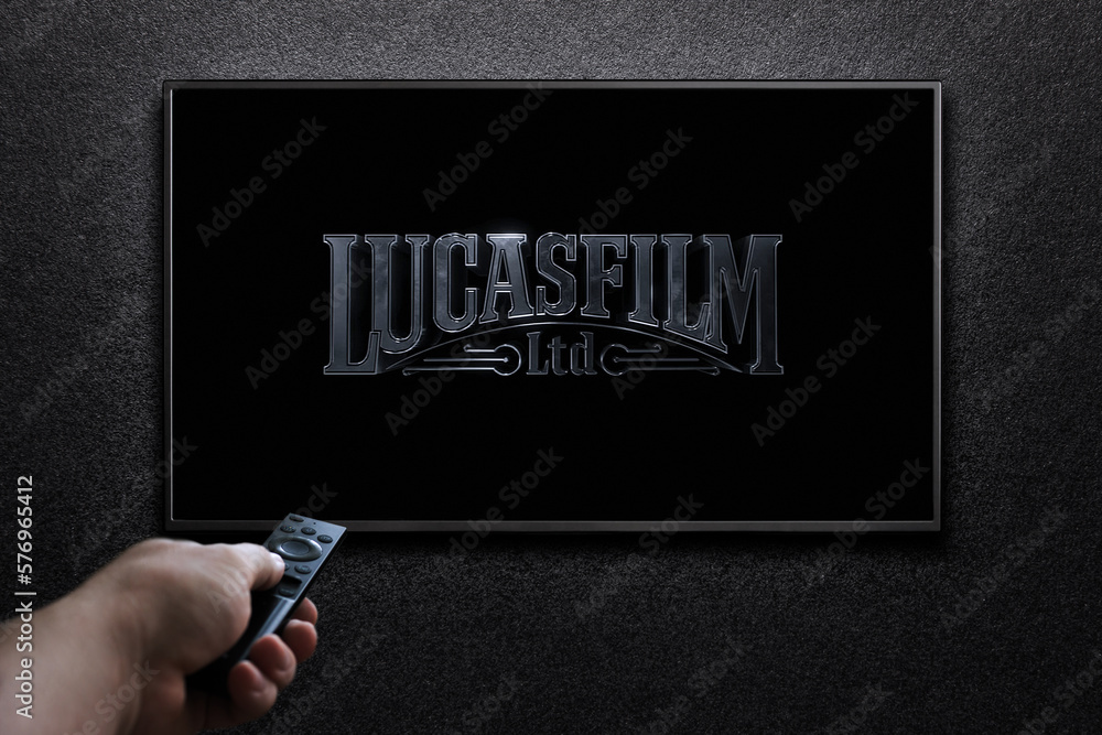 Fototapeta premium TV screen playing Lucasfilm movie. Man turns on TV with remote control. Moscow, Russia - January 18, 2023.