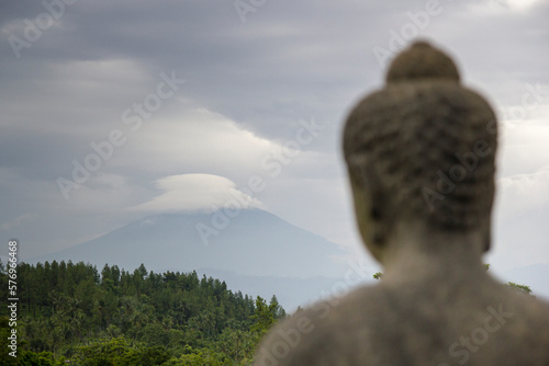 A statue of Budhha looking at Mt Merapi in the distance. photo