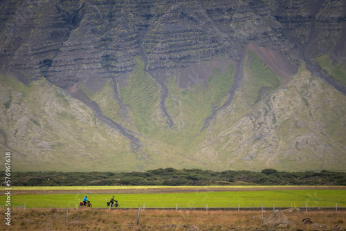 People riding bicycles in scenery with volcanic mountain, Eldborg, Snaefellsnes, Iceland photo