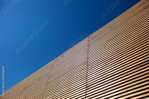 Wall of wooden slats on a sky background. Wooden floor. Wooden fence. Wooden wall. Modern architectural wall.