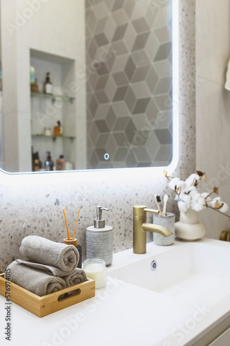 luxury modern bathroom interior with gold tap  faucet   grey stone walls  hand towels and liquid soap. Scandinavian minimalistic style.