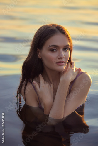 Beautiful young woman in the water at sunset. Natural beauty, long hair, woman in the lake