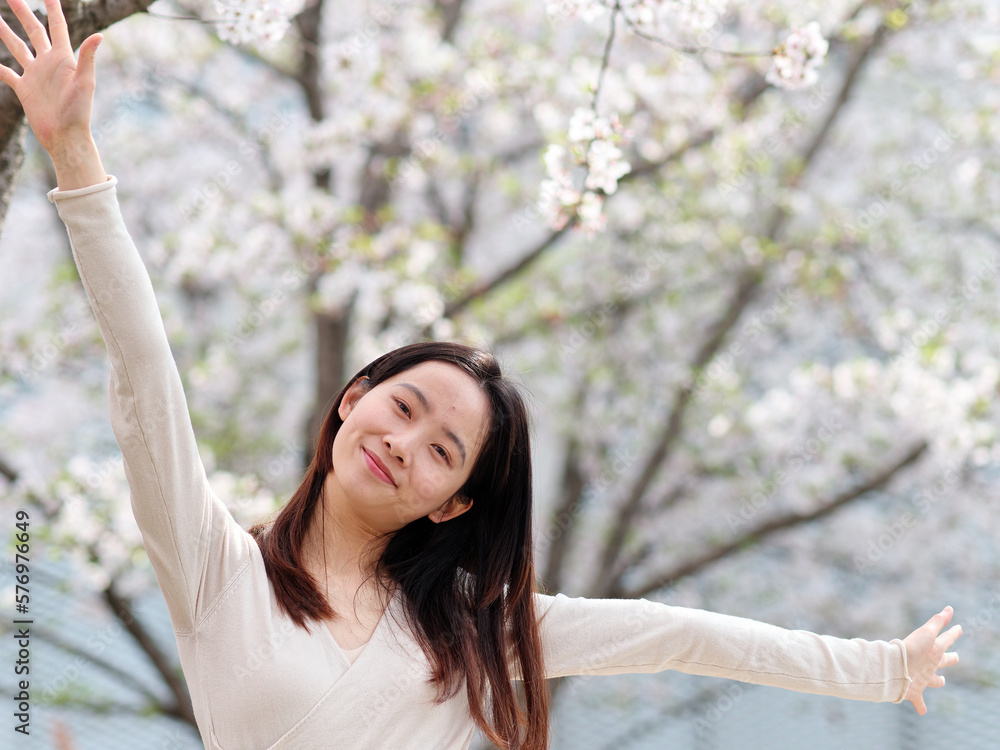Outdoor portrait of beautiful young Chinese girl posing with blossom white cherry flowers background in spring garden, beauty, summer, emotion, lifestyle, expression and people concept. Outdoor portrait of beautiful young Chinese girl posing with blossom white cherry flowers background in spring garden, beauty, summer, emotion, lifestyle, expression and people concept.