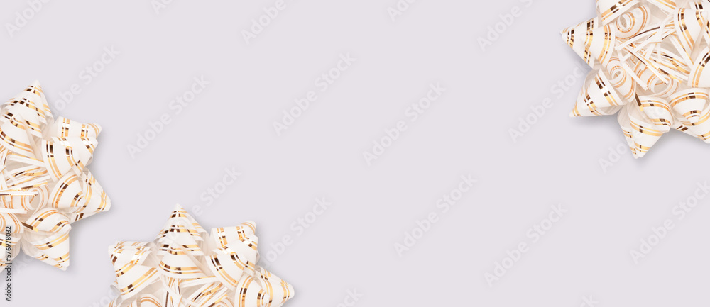 Fototapeta premium Banner with golden ribbon bows scattered on a blue background.
