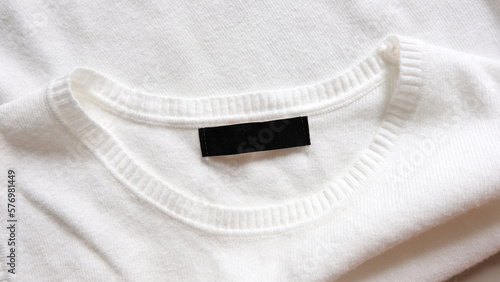 Black blank clothing tag label on new white shirt background 