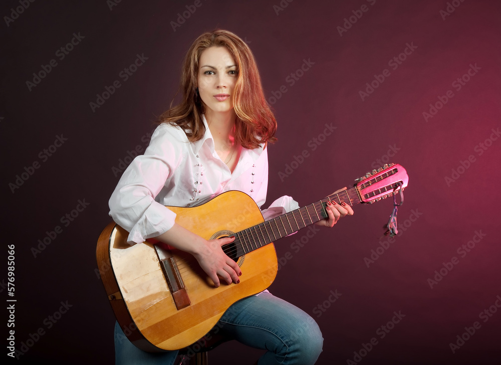 Fototapeta premium Attractive girl, woman playing guitar in the studio.