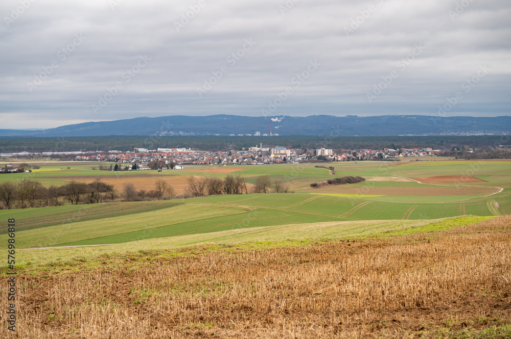 Cityscape of Schaafheim, with agricultural fields in the front and Mountain range in the background during cloudy day, Germany