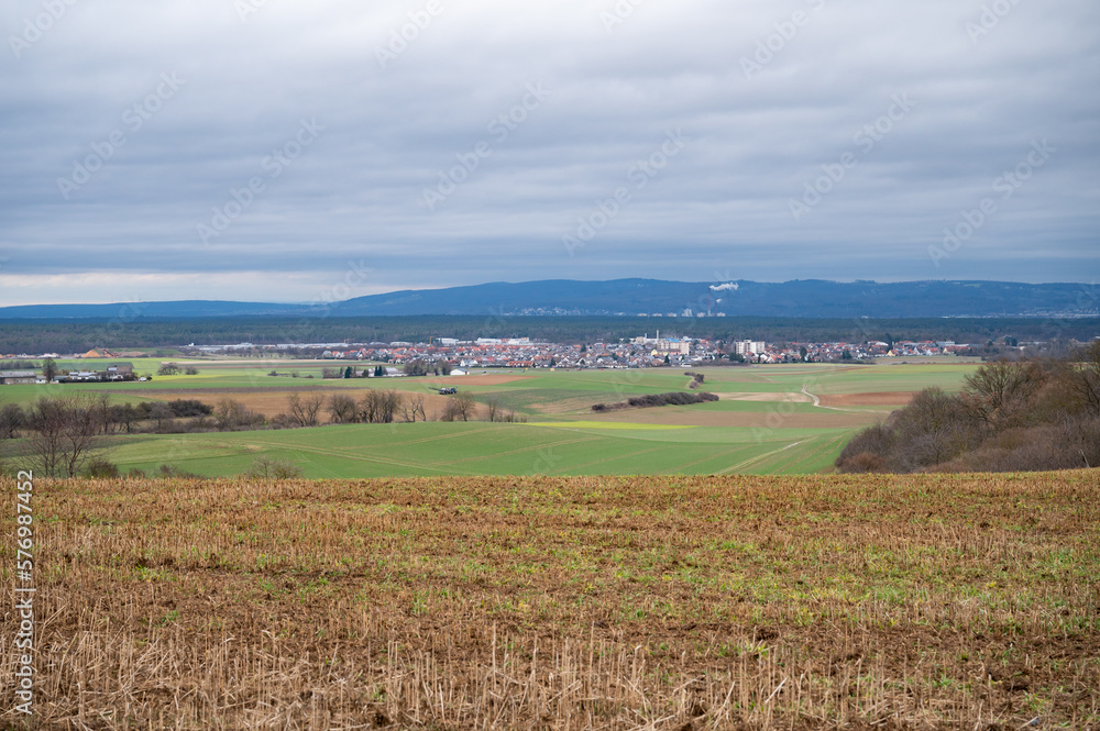 Cityscape of Schaafheim and village next to it, with agricultural fields in the front and Mountain range in the background during cloudy day, Germany