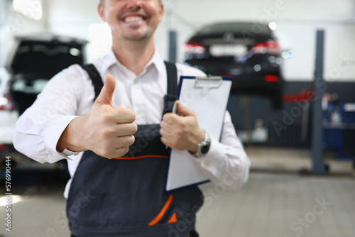 Portrait of male mechanic showing thumbs up in car service © H_Ko
