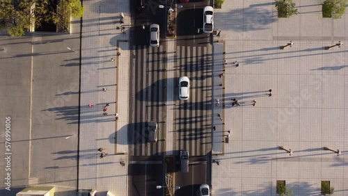 Aerial Drone view over traffic cars and a crowd of pedestrians crossing street in a sunset light.
