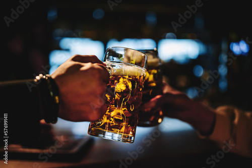 man and woman hands clinking glasses of light beer at the pub or bar