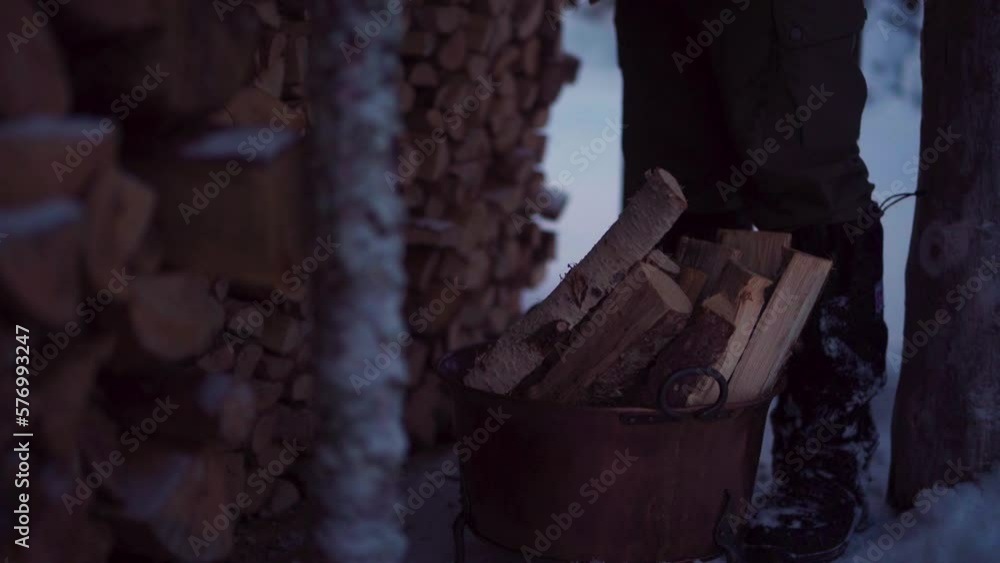 Man Standing Next To Chopped Firewood In Rusty Bucket In Winter. closeup Man Standing Next To Chopped Firewood In Rusty Bucket In Winter. closeup