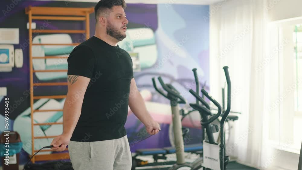 Strong young man using a jumping rope to improve muscle strength and cardio routine in the gym Strong young man using a jumping rope to improve muscle strength and cardio routine in the gym