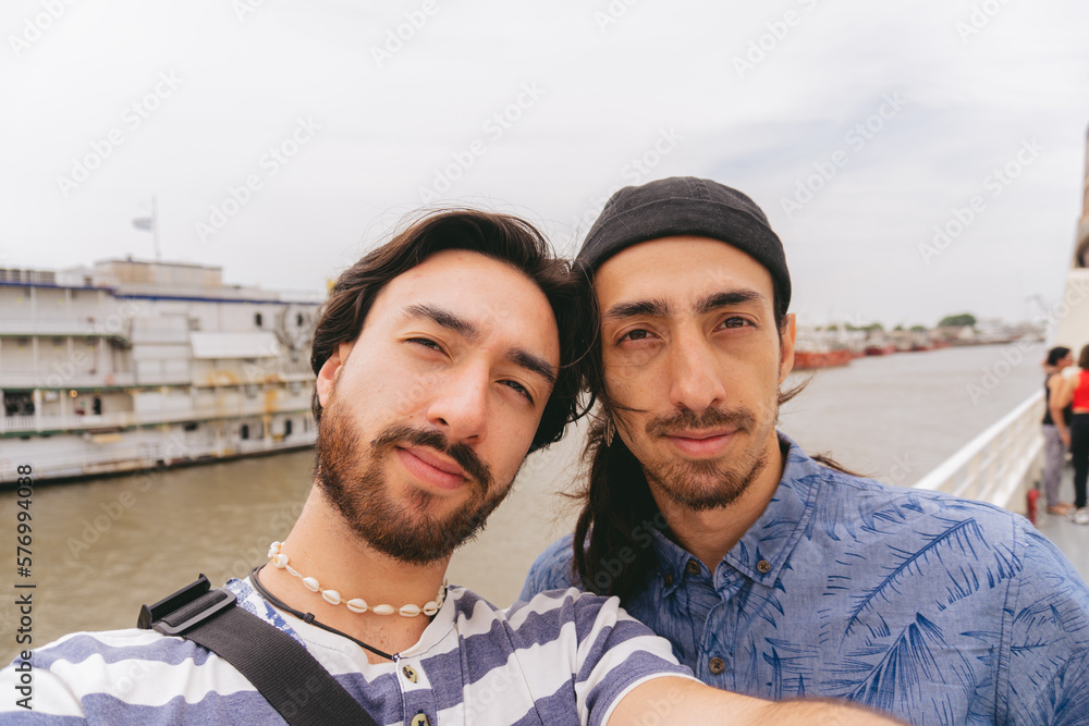 Young latin brothers looking at camera while taking a selfie on a pier. Young latin brothers looking at camera while taking a selfie on a pier.