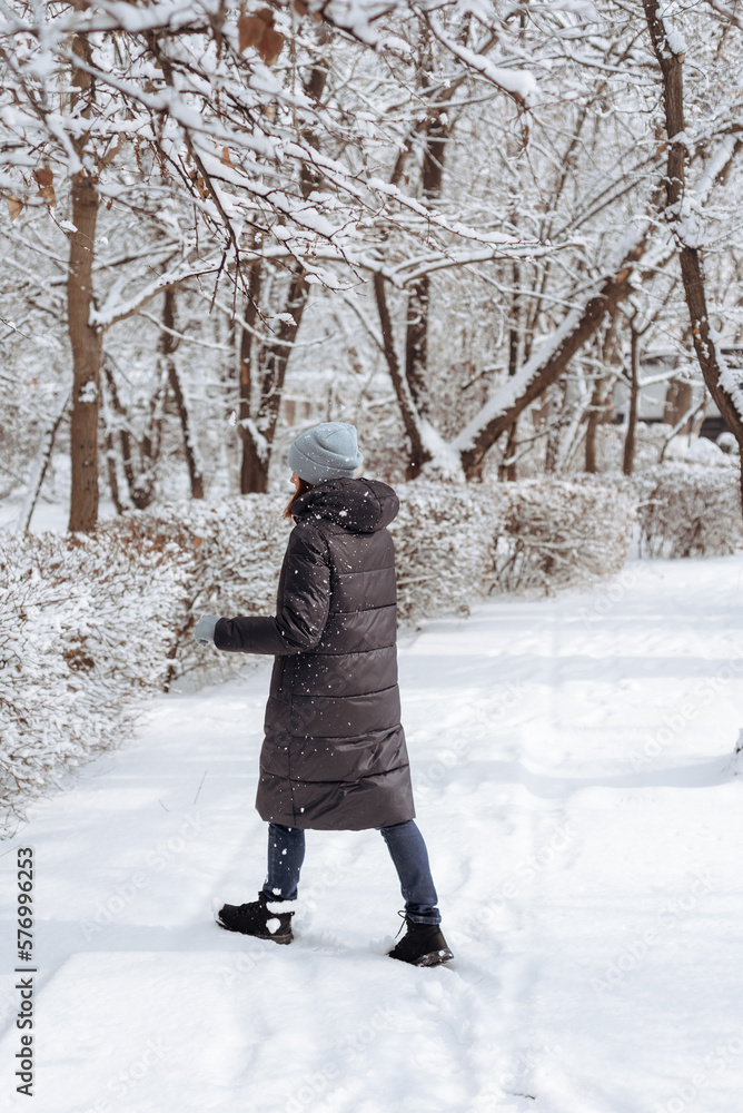 A woman stands in warm clothes in a winter park. Walk in winter. A woman stands in warm clothes in a winter park. Walk in winter.