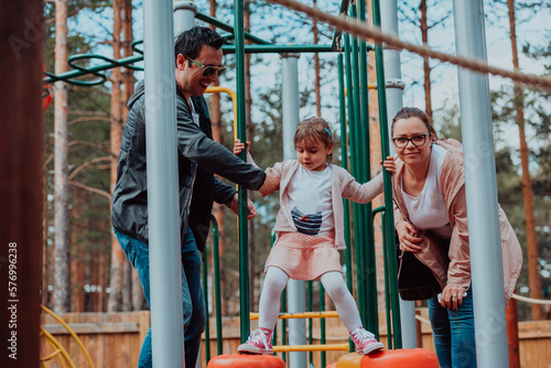 Family fun in the park. Happy family spending time in park and playing with their daughter