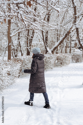 A woman stands in warm clothes in a winter park. Walk in winter.